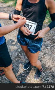 Girl placing the race number with the help of a teammate. Girl placing the race number