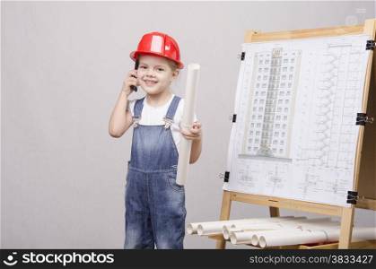 Girl playing Builder talking on the phone behind the blackboard with a drawing of a house