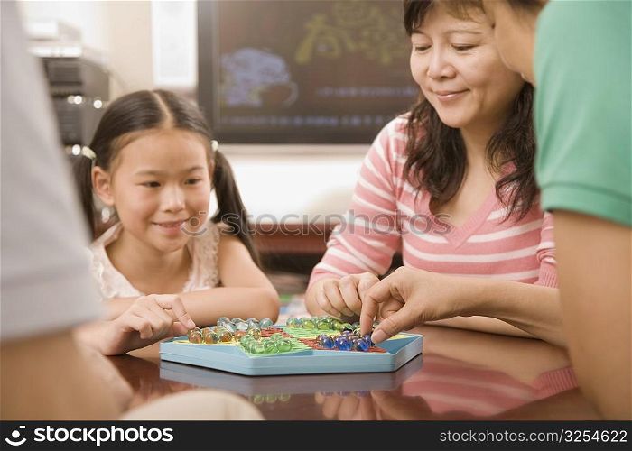 Girl playing Chinese checkers with her mother
