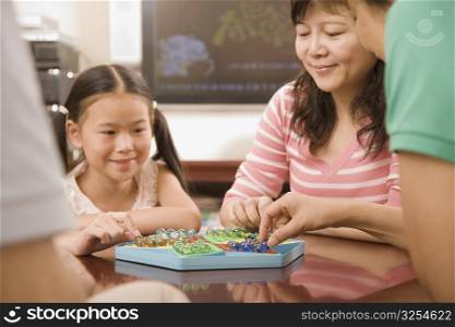 Girl playing Chinese checkers with her mother