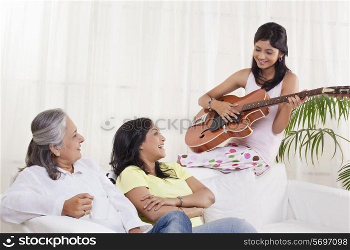 Girl playing guitar for her mother and grandmother