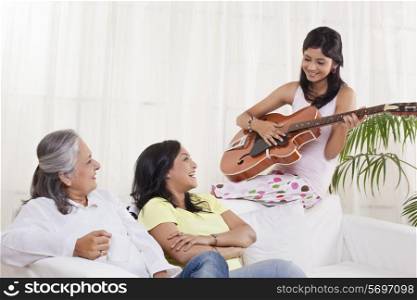 Girl playing guitar for her mother and grandmother