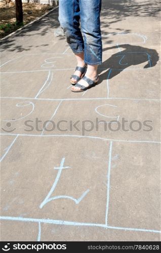 girl playing in hopscotch on urban alley in sunny day