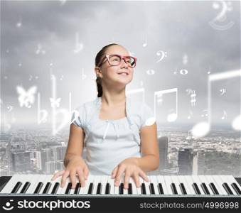 girl playing on an old black.... Young girl sitiing at digital piano with red glasses