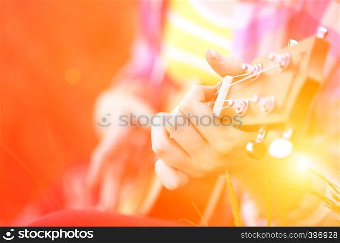 girl playing on ukulele. hands playing a guitar close-up