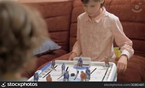 Girl playing table hockey with brother, she concentrated on the game. Home leisure activities