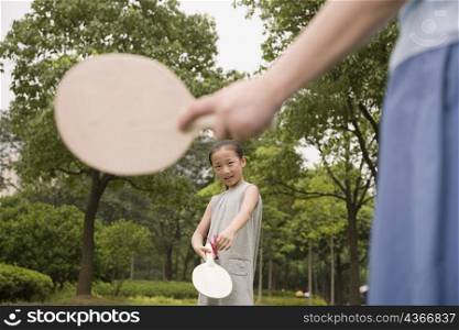 Girl playing tennis with her mother in a garden