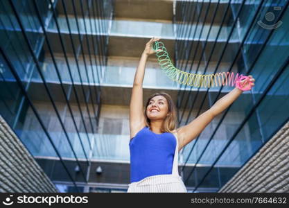 Girl playing with a colorful spring toy in urban background. Girl playing with a colorful spring toy outdoors