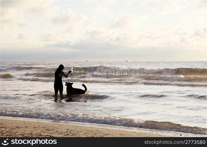 girl playing with bottle and dog in the sea