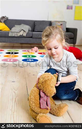 Girl playing with teddy bear at home