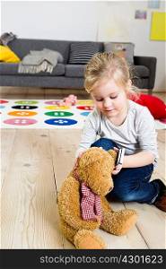 Girl playing with teddy bear at home