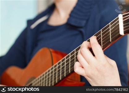 girl plays on modern acoustic guitar close up