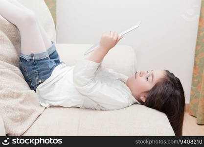girl plays with a tablet on the sofa and hallway of his house