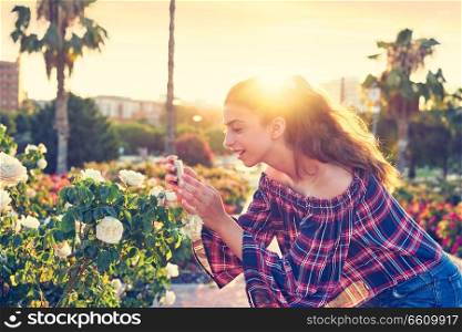 Girl portrait taking photos to a rose flower with smarphone