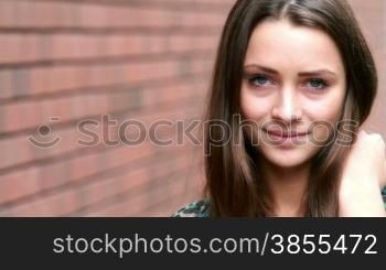 girl posing against a brick wall.