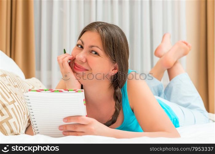 girl posing on a bed with notebook in hand