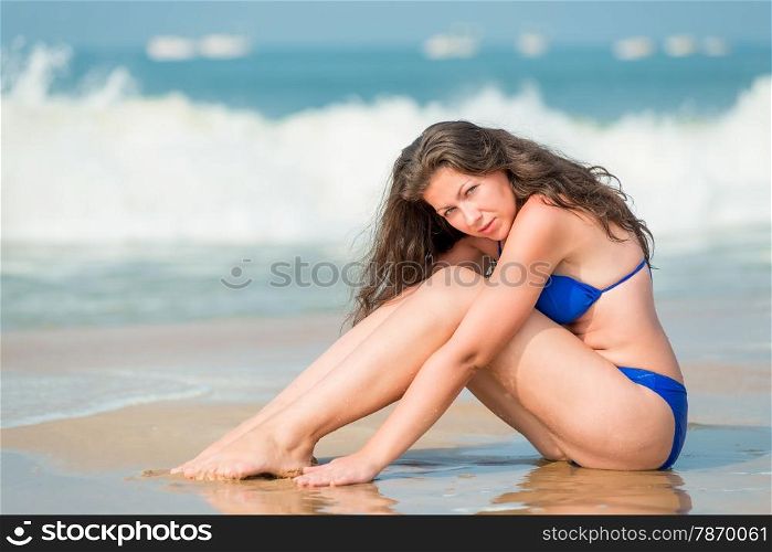 girl posing sitting on the wet sand of the sea
