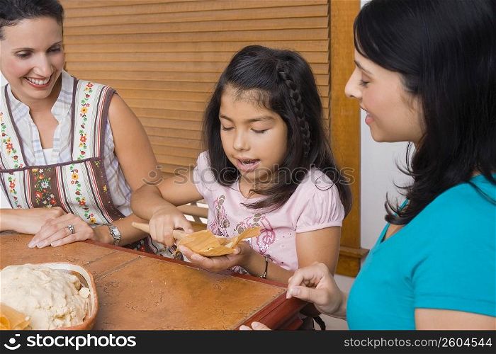 Girl preparing bread with her mother and sister in the kitchen