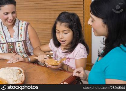 Girl preparing bread with her mother and sister in the kitchen