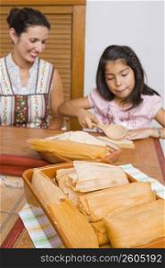 Girl preparing bread with her mother in the kitchen