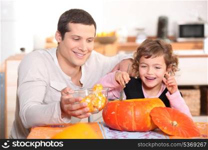 Girl preparing pumpkin with father