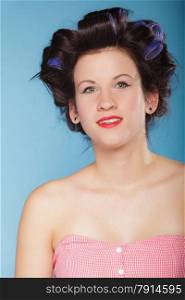 Girl preparing to party. Headshot of young woman with hair curlers pin up makeup studio shot on blue