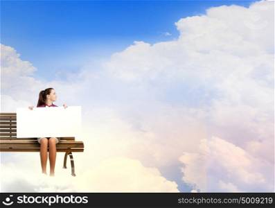 Girl presenting something. Young woman with white blank banner sitting on bench