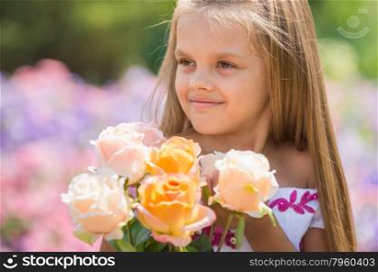 Girl princess in a beautiful dress holding a bouquet of roses. Happy six year old girl in a lush evening pink dress walking through the green garden