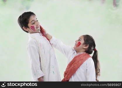 Girl putting colour on a boy&rsquo;s face