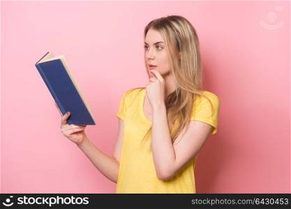 Girl reading a book and thinking near pink wall