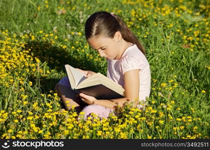 Girl reading a book on the grass