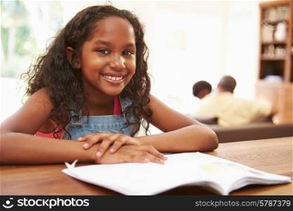 Girl Reading Book For Homework At Table