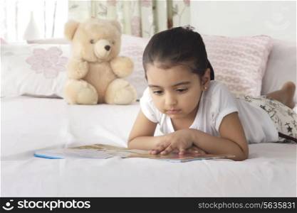 Girl reading book while lying in bed