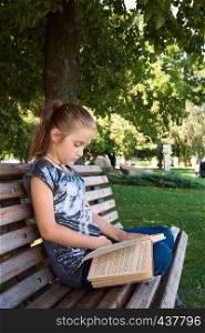 girl reading on a bench at the park.