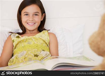 Girl reading story to teddy bears sitting on bed half length