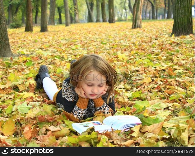 girl reads a book in the autumn park. young girl reads a book in the autumn park young girl reads a book in the autumn park lying on the ground