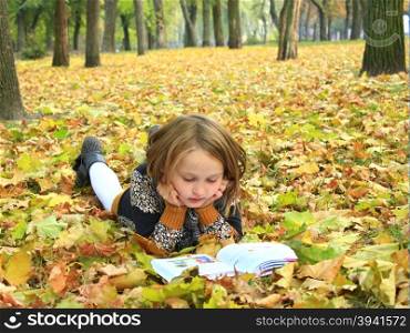 girl reads a book in the autumn park. young girl reads a book in the autumn park young girl reads a book in the autumn park lying on the ground
