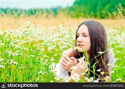girl resting in a field of chamomile in a white dress