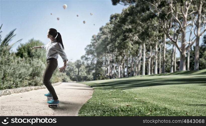 Girl ride skateboard. Active girl riding skateboard on road in park