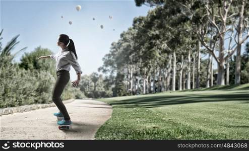 Girl ride skateboard. Active girl riding skateboard on road in park