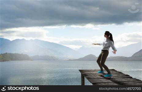 Girl ride skateboard. Active girl riding skateboard on wooden pier