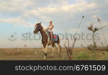 Girl rides a horse through the field
