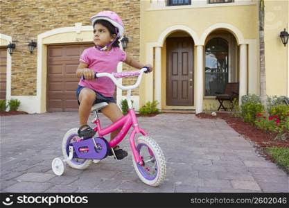 Girl riding a bicycle in front of a house