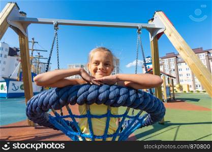 Girl riding a round hanging swing in the playground