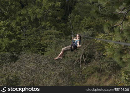 Girl riding a zip line in a forest, Copan, Copan Ruinas, Copan Department, Honduras