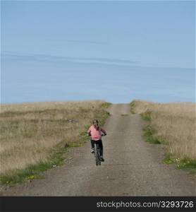 Girl riding bicycle on empty rural road
