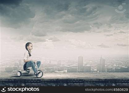Girl riding bike. Little cute girl of preschool age riding tricycle