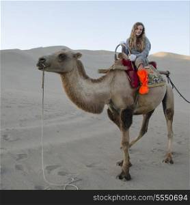 Girl riding camel at Mingsha Shan, Dunhuang, Jiuquan, Gansu Province, China