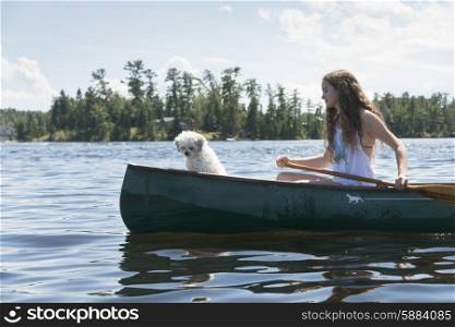 Girl rowing a canoe with a puppy, Lake of the Woods, Ontario, Canada