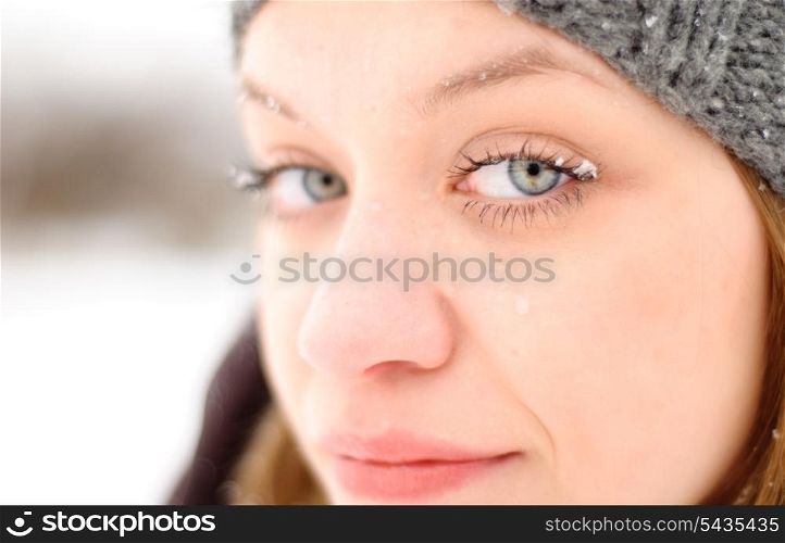 Girl&rsquo;s face with blue eyes under snow outdoors. Close up portrait